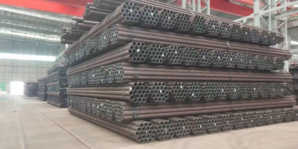 Neatly stacked seamless steel pipe bundles in an indoor warehouse