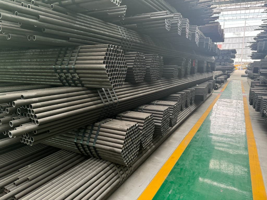 Bundled seamless steel tube racked along an epoxy-floored warehouse aisle