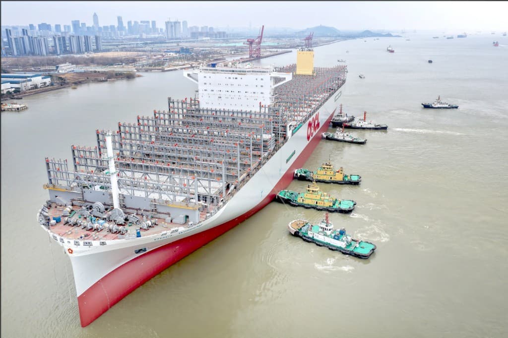Large container ship under construction escorted by tugboats