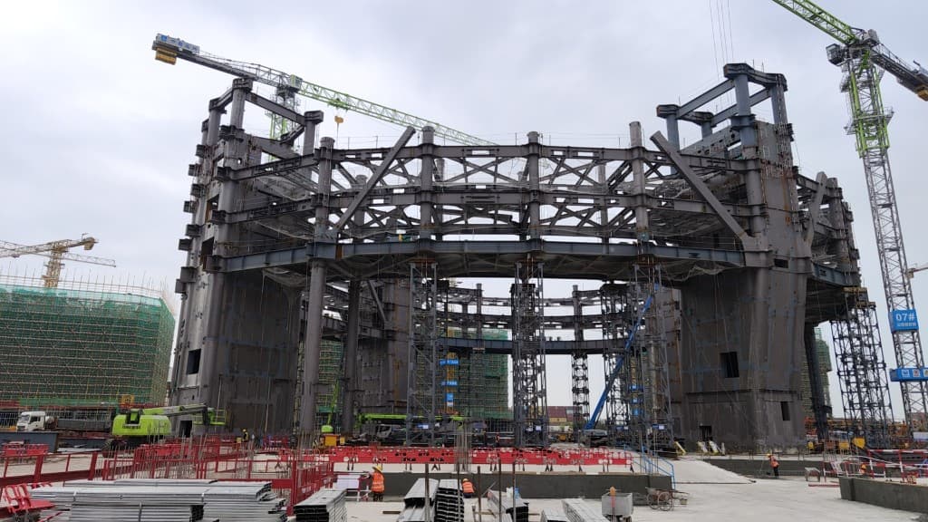 Heavy steel structure under construction with tower cranes on site